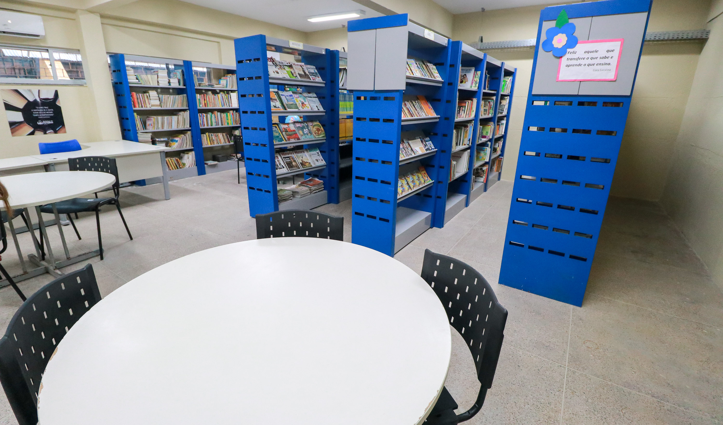 biblioteca com mesas redondas e estantes de livros ao fundo